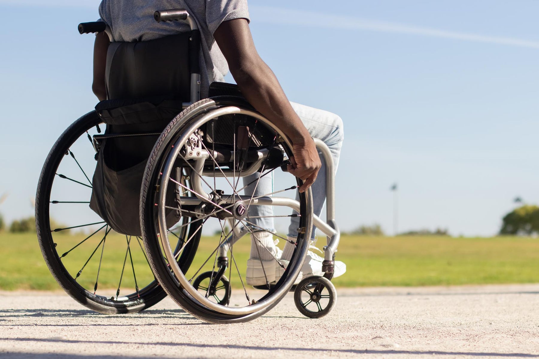 black-man-wheelchair-riding-along-park-road